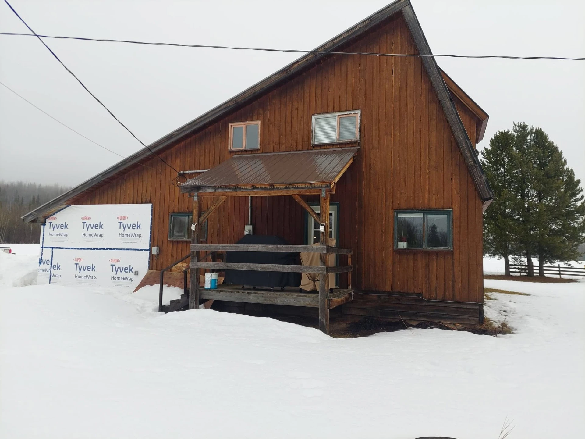 Stained board-and-batten cabin with covered timber deck in winter