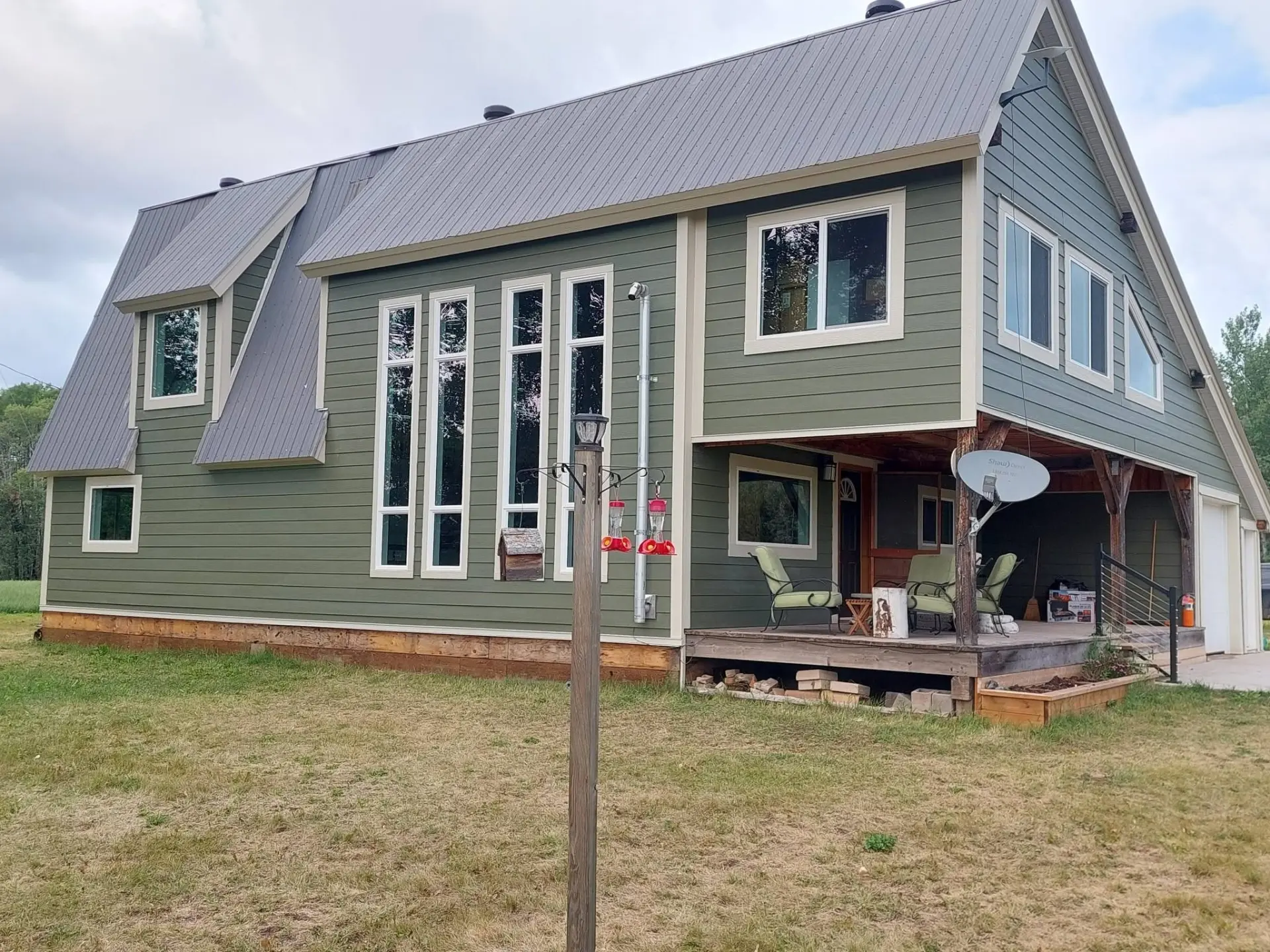 Two-storey home with new green siding and cream trimmed windows