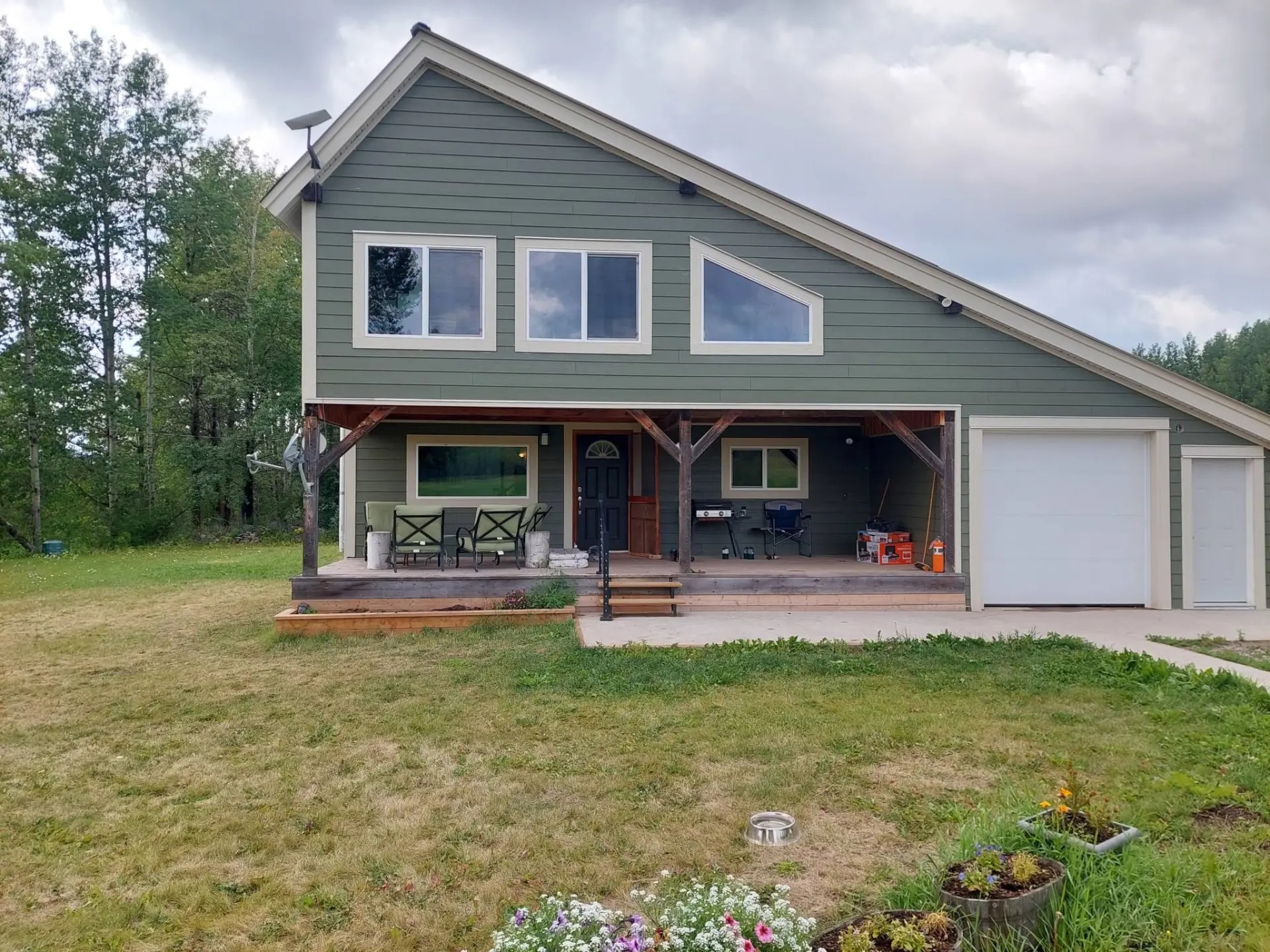 Green-sided timber-frame home with covered porch and attached garage